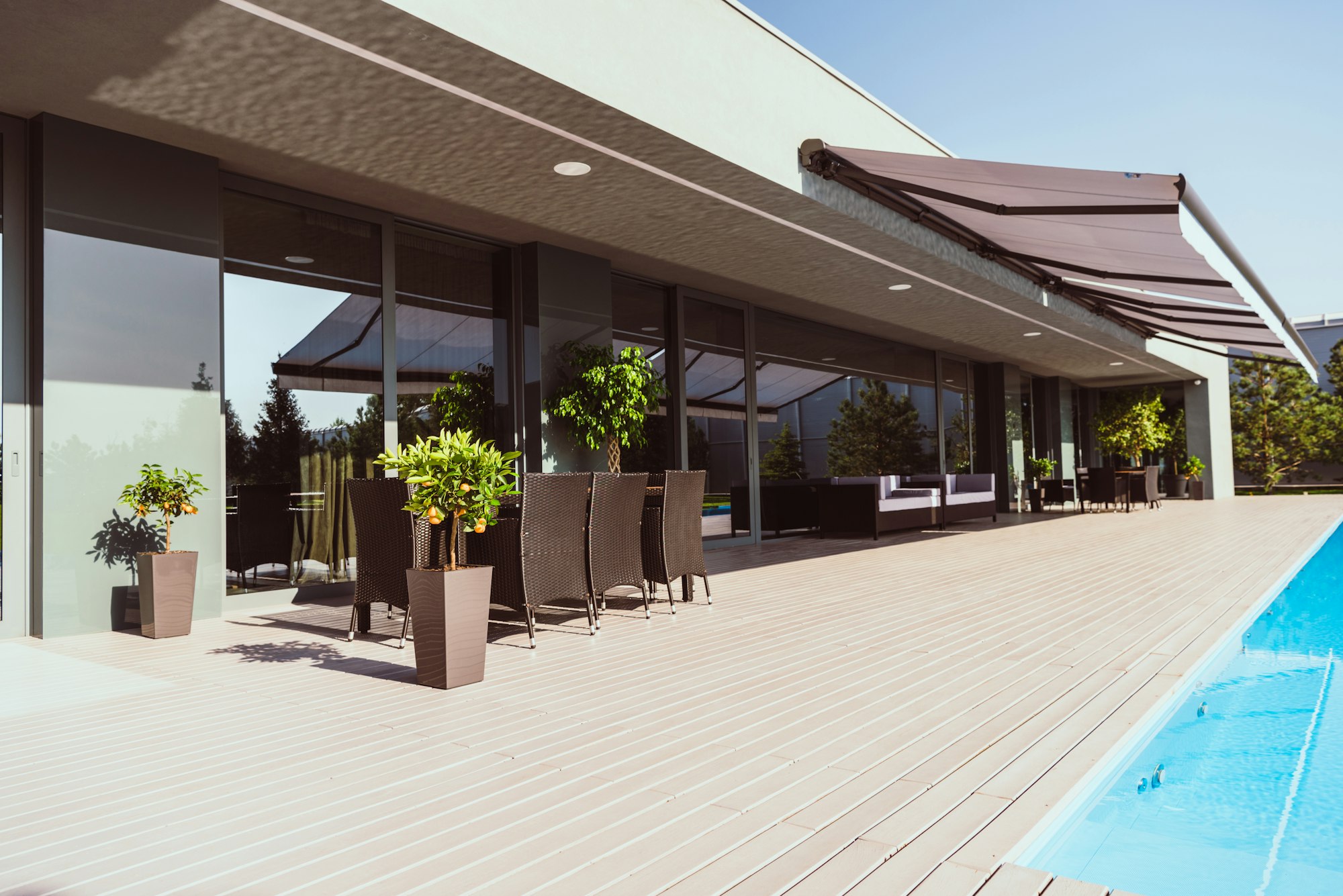 swimming pool and porch of modern country house with little trees, chairs and tables